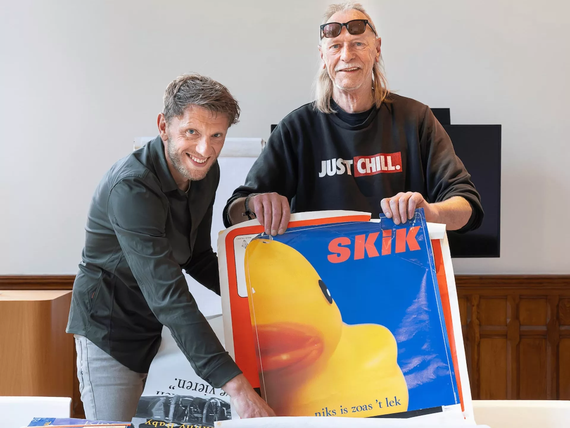Ferry Sieders van Drents Archief en Jan Stam van K&C poseren met een poster van SKIK.