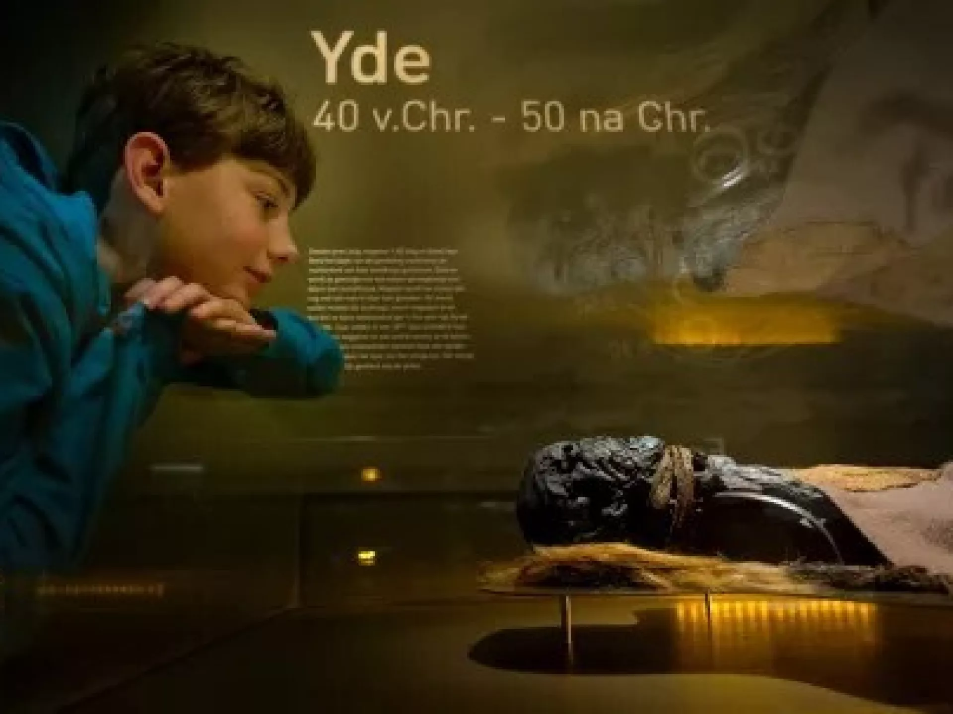 Jongen kijkt naar de Yde-mummie in een museum.