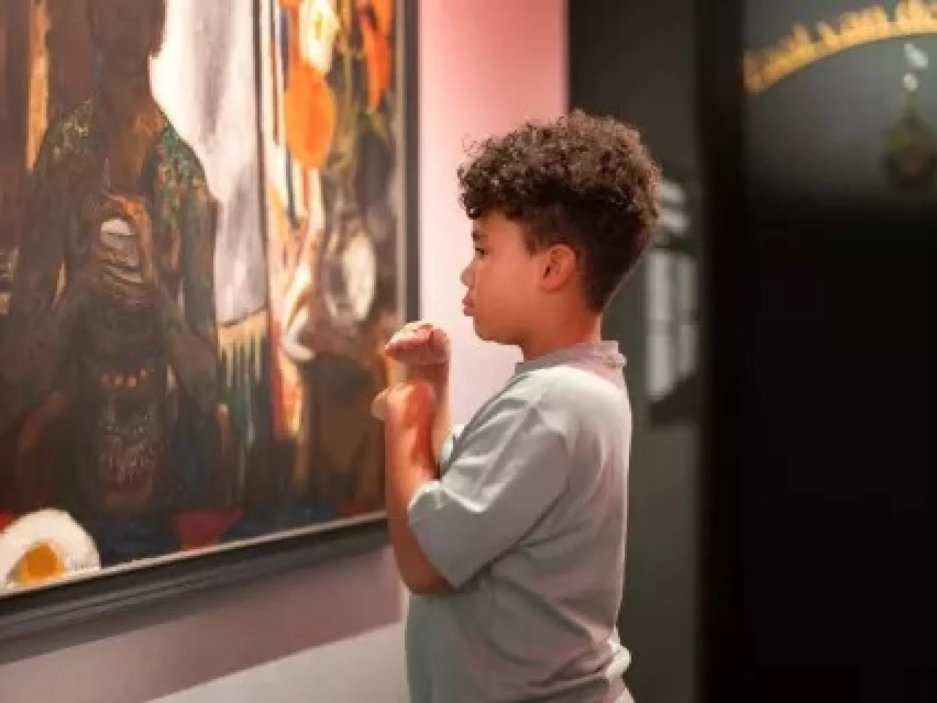 Een jongen bewondert een schilderij in een kunstgalerij.