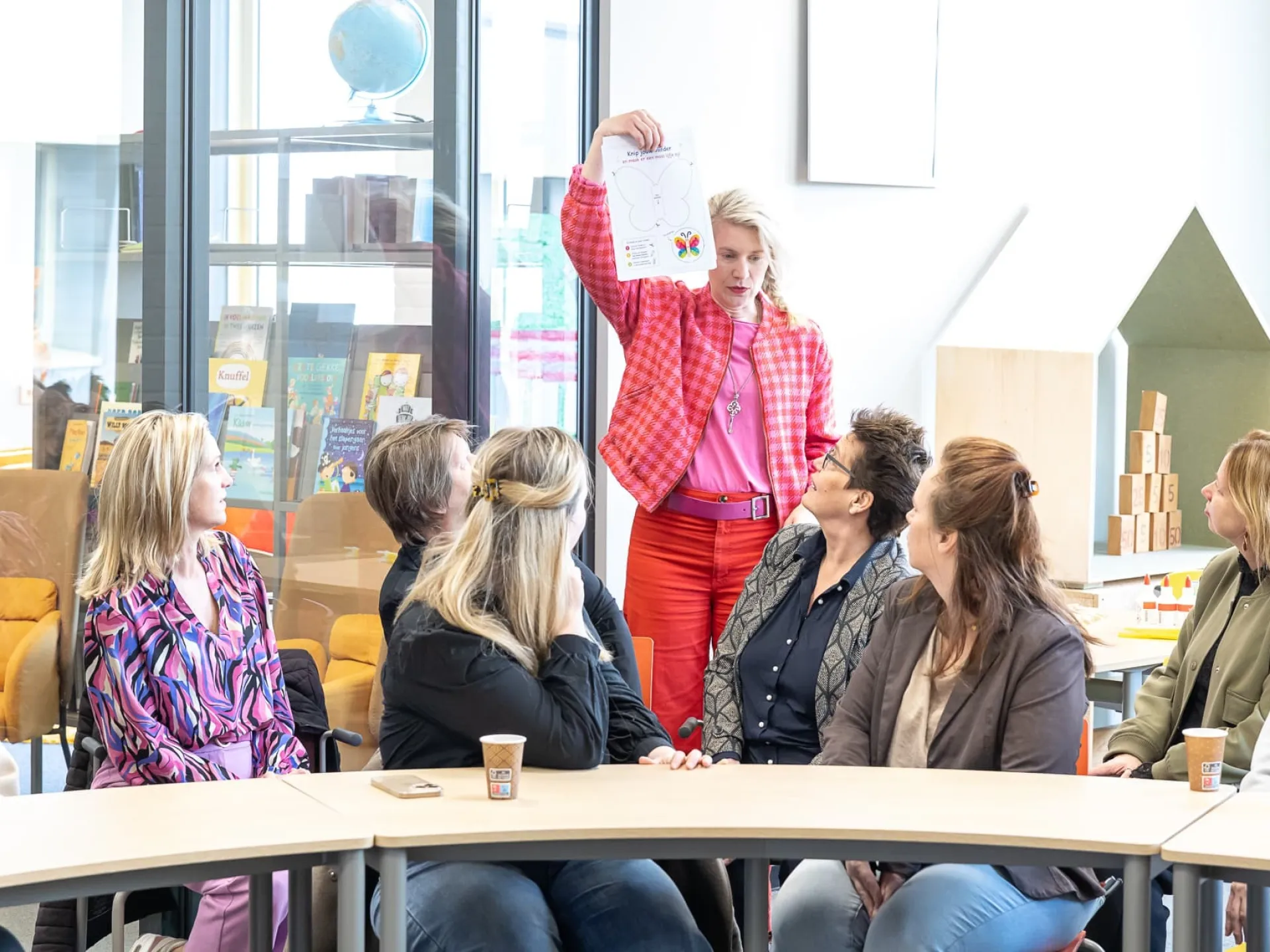 Een vrouw presenteert iets aan een groep mensen in een vergaderruimte.
