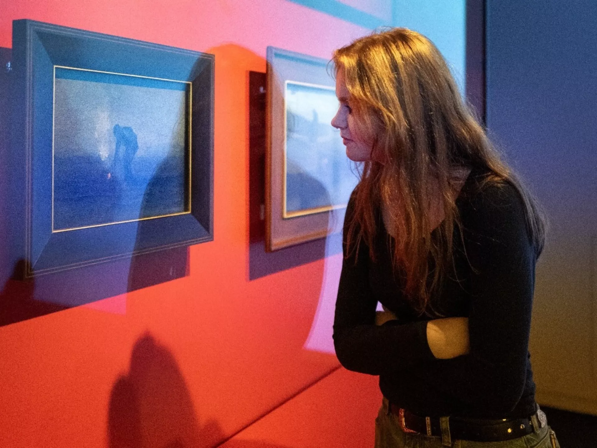 Een persoon kijkt aandachtig naar schilderijen in een kunstgalerie.