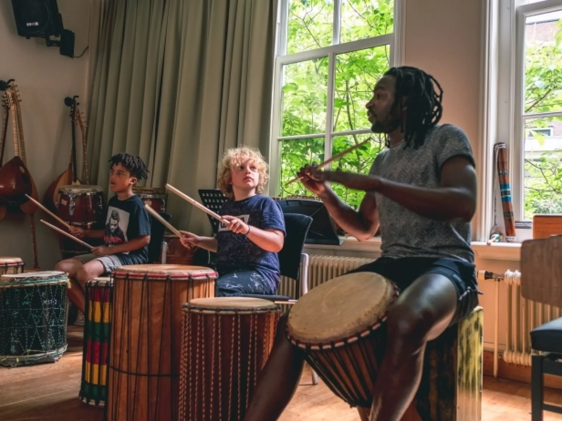 Mensen spelen op drums in een muzieklokaal.