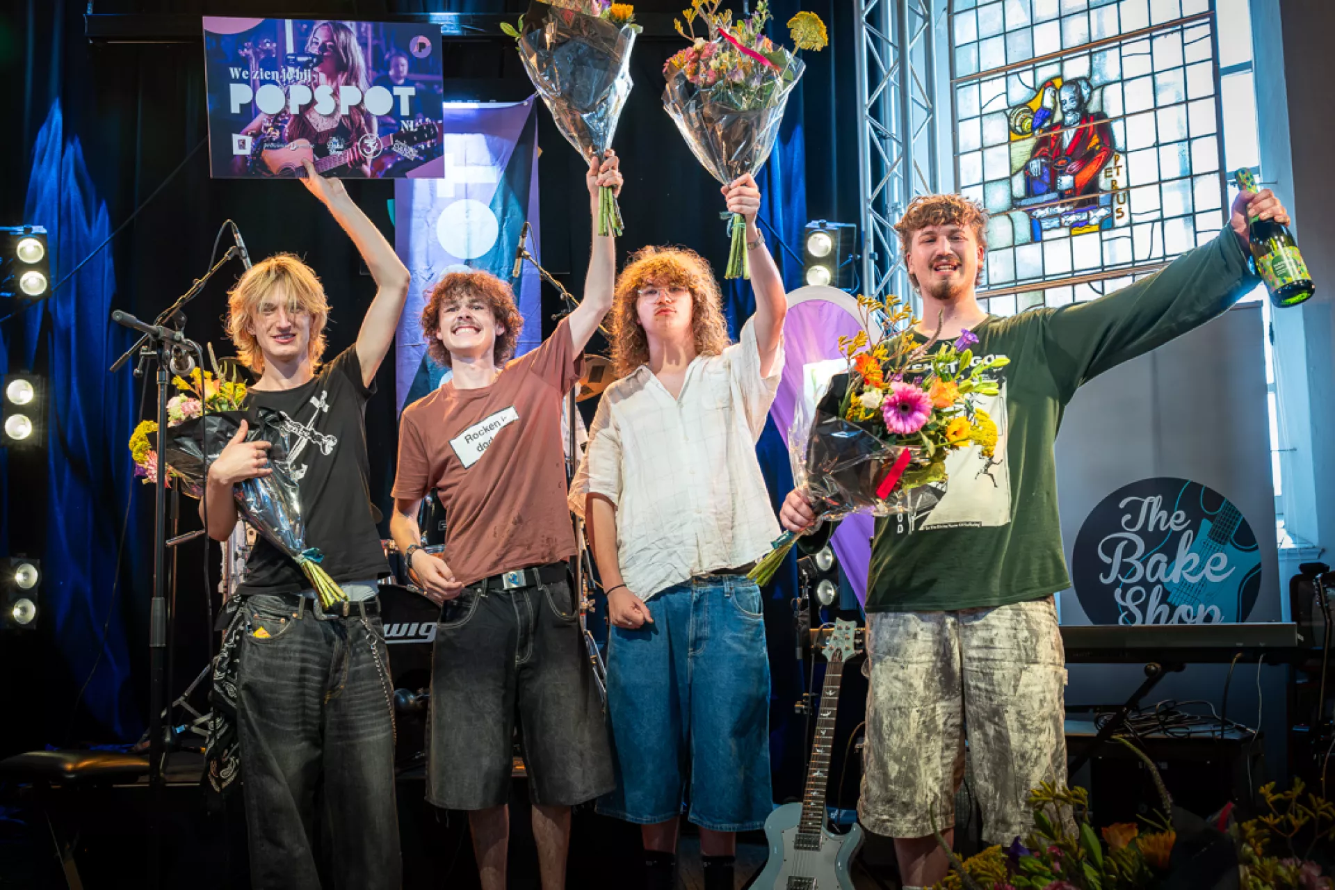 De winnende band op een podium met bloemen en verheffen hun handen in vreugde.