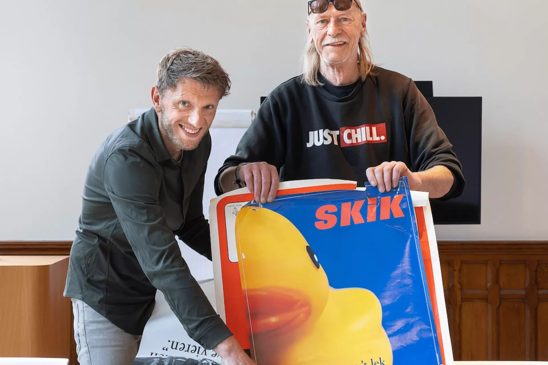 Ferry Sieders van Drents Archief en Jan Stam van K&C poseren met een poster van SKIK.