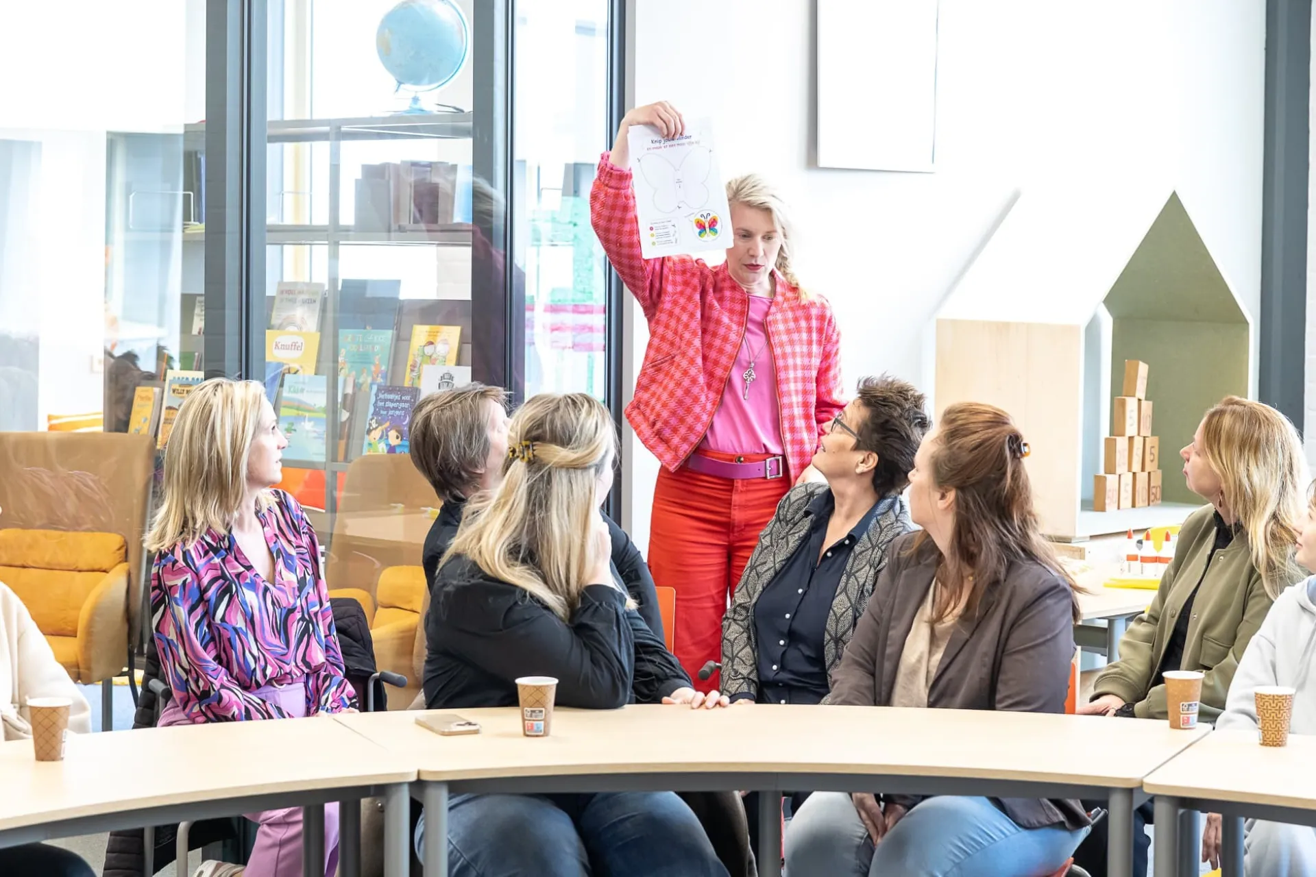 Een vrouw presenteert iets aan een groep mensen in een vergaderruimte.