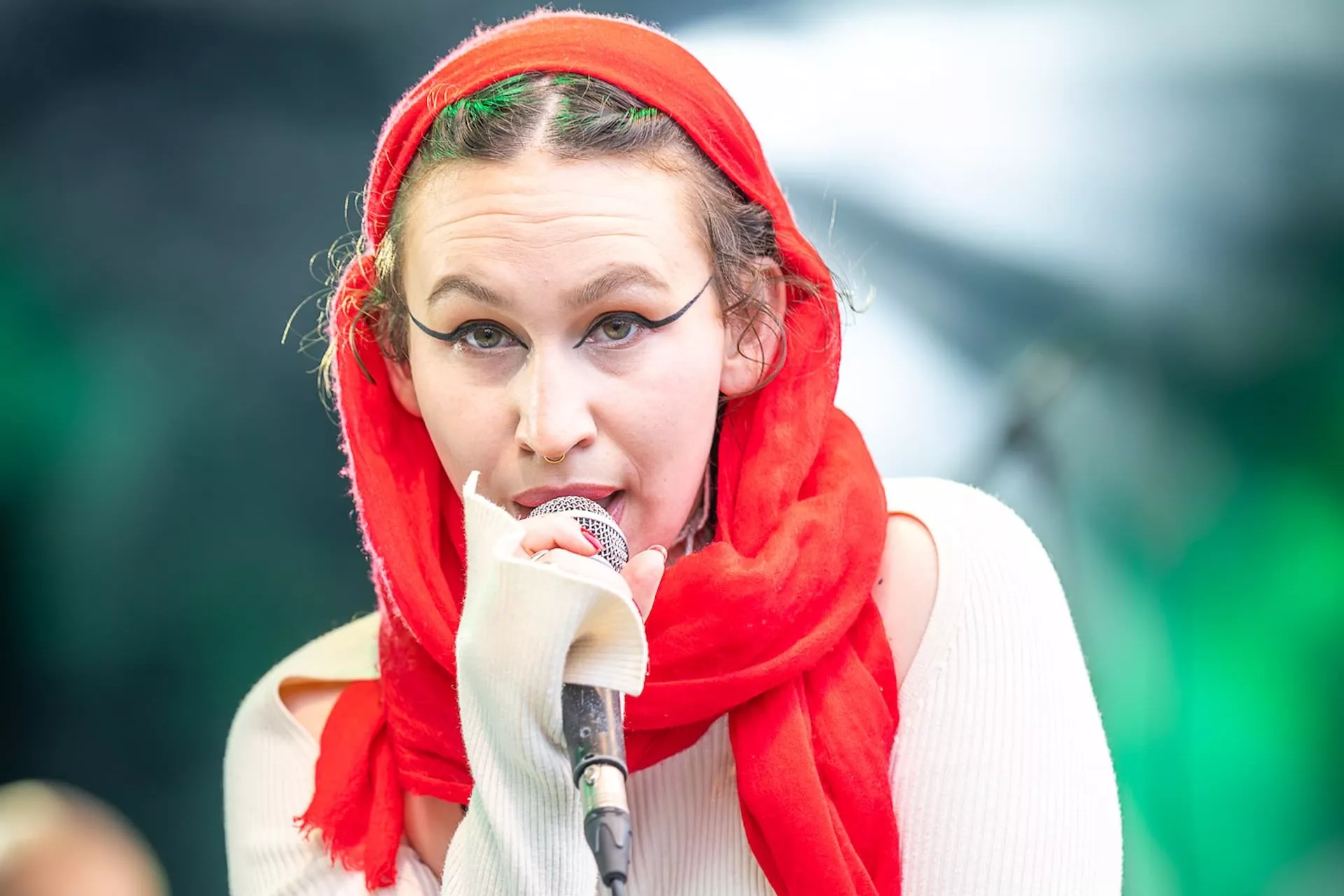 Vrouw zingt met rode sjaal op podium.