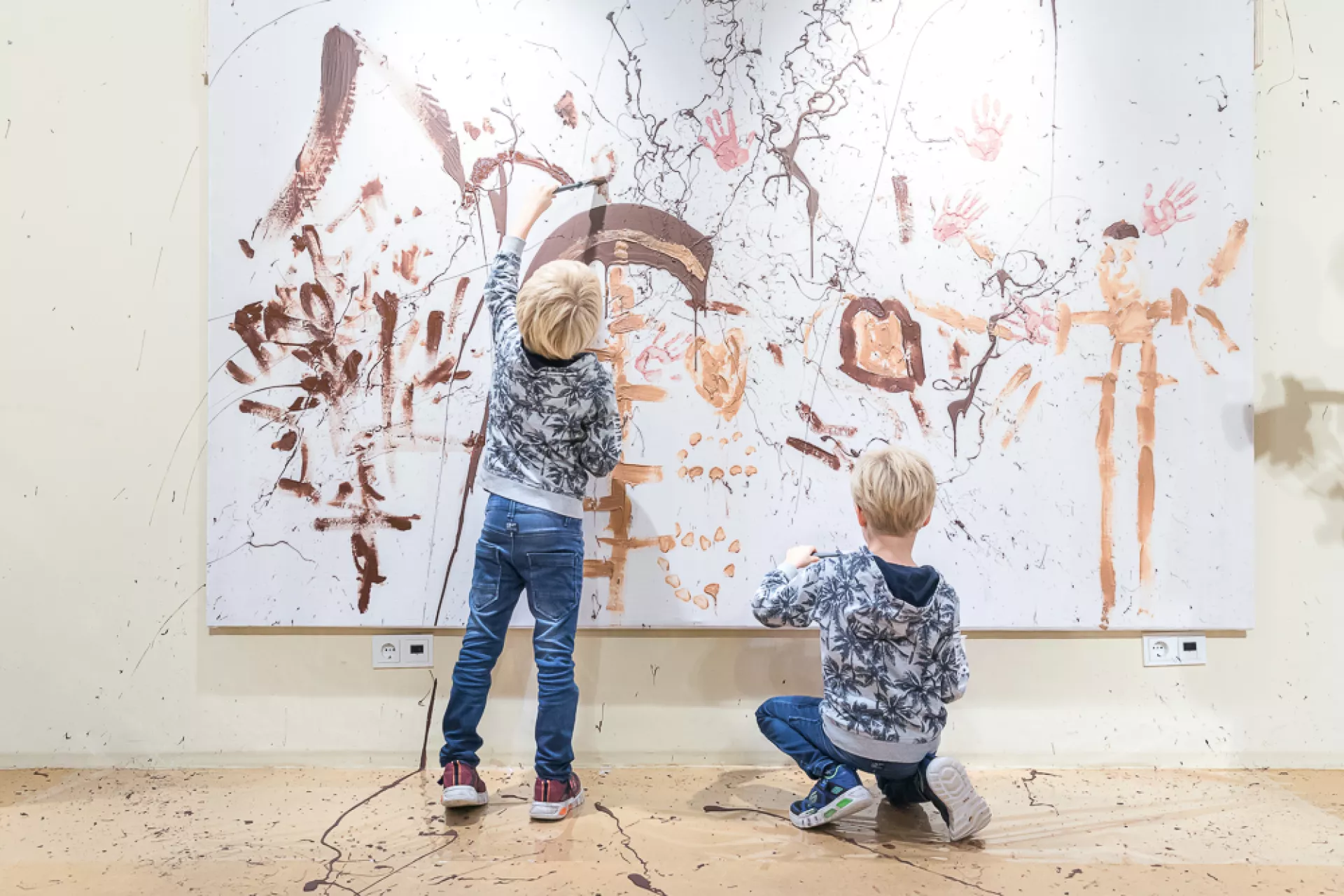 Twee kinderen maken een schilderij op een groot doek in een kunststudio.