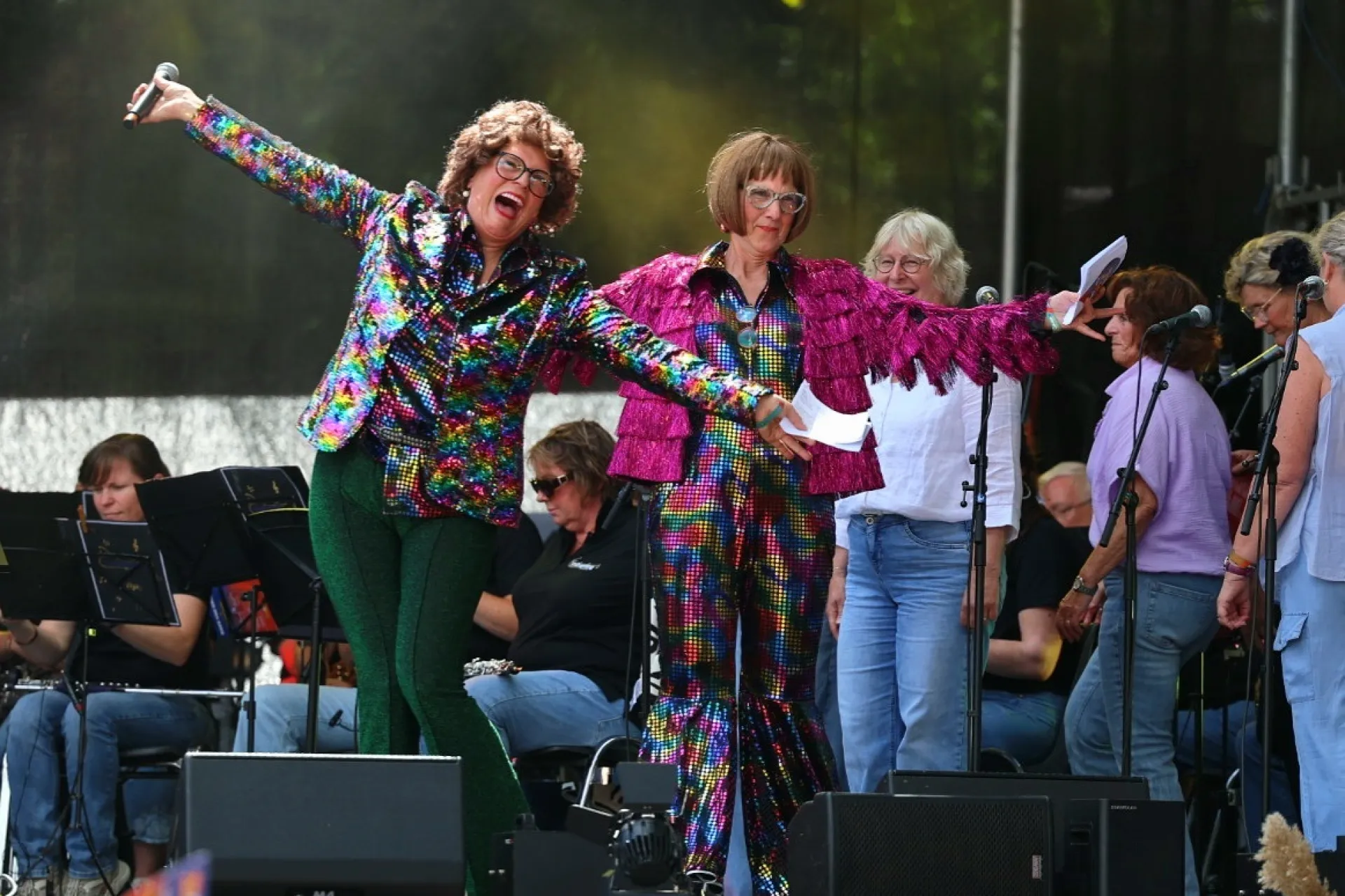 Twee mensen in kleurrijke kostuums optreden op een podium tijdens een festival.